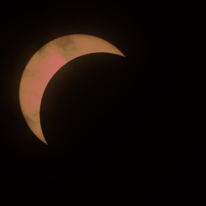 The sun with a bit more than three quarters blocked by the moon, leaving a crescent in the top left
