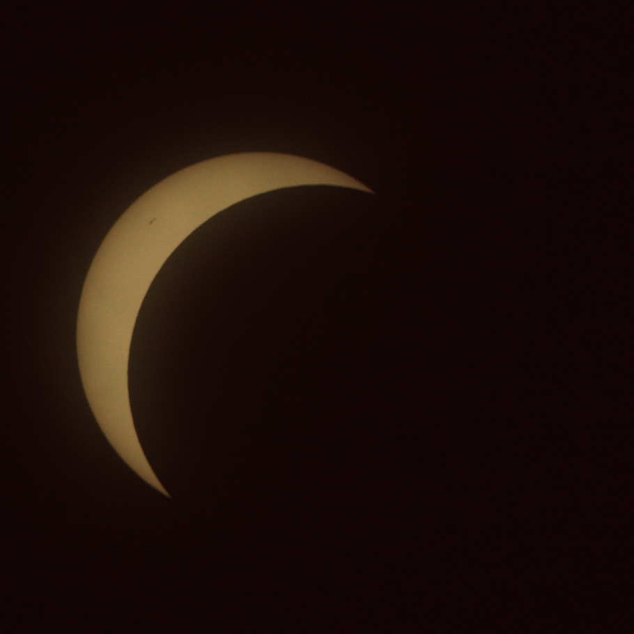 The sun with a bit more than three quarters blocked by the moon, leaving a crescent in the top left