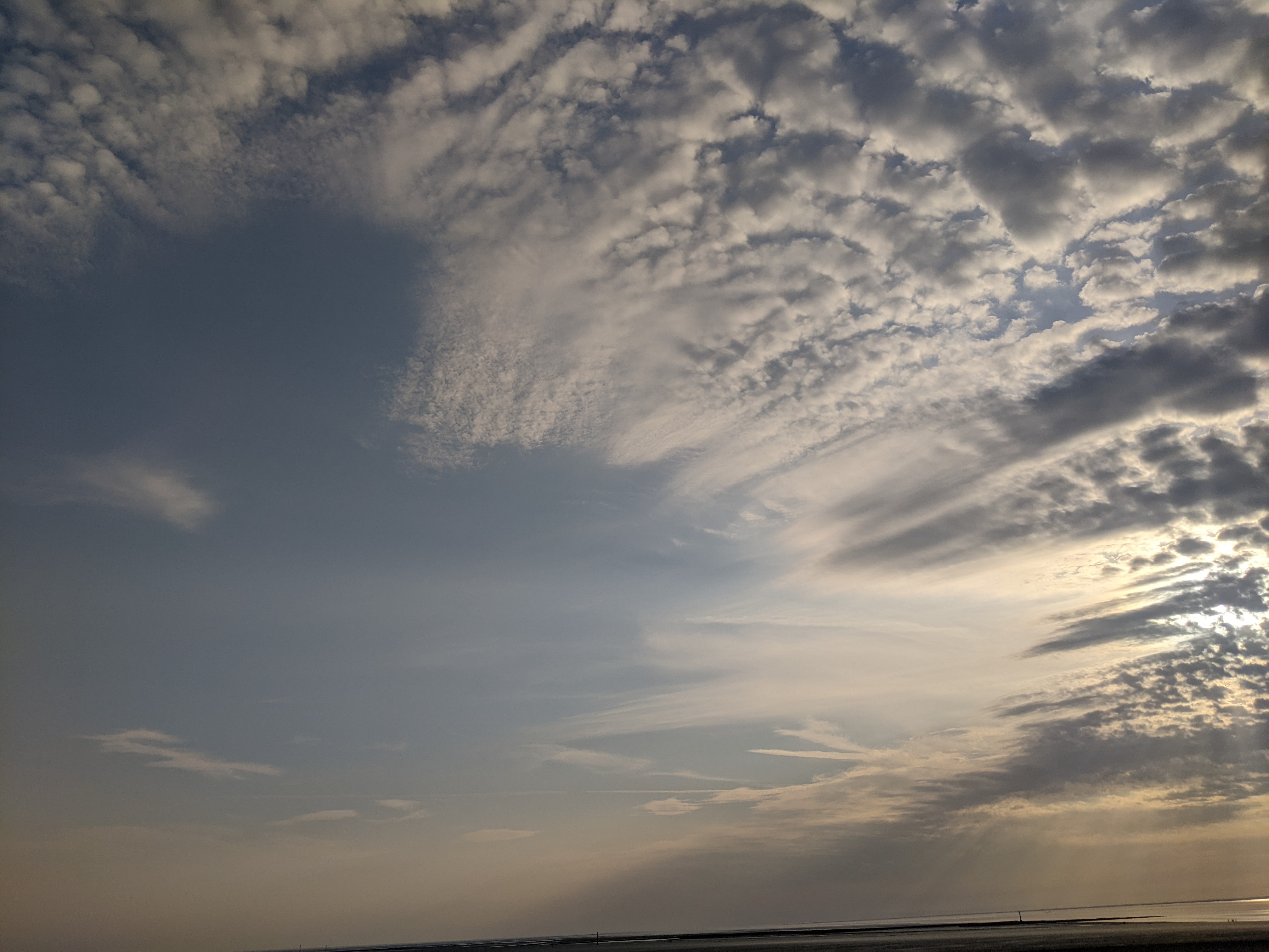 A shot of the clouds, with the obscured sun visible on the right edge of the frame